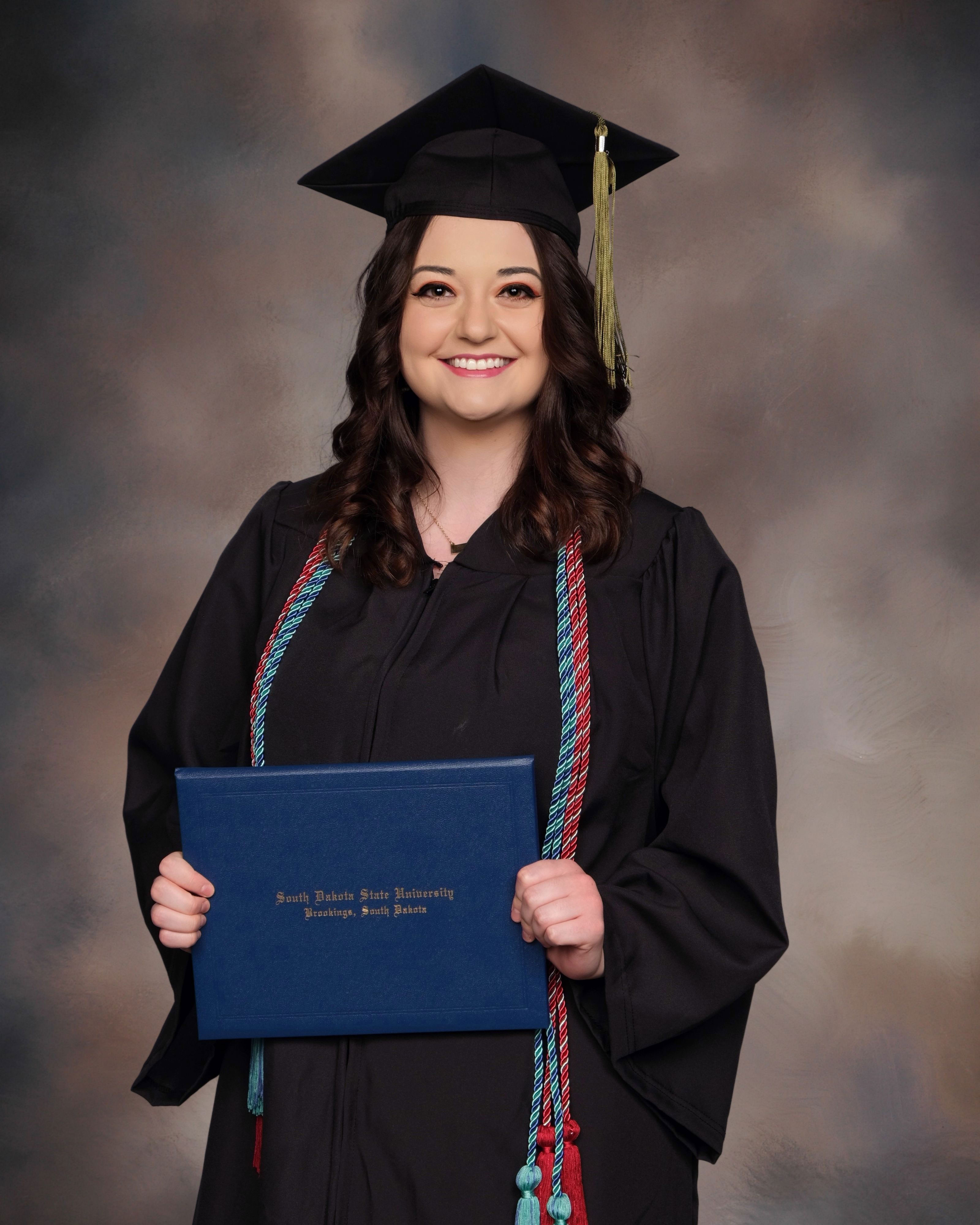 Photo of Kaylen holding her diploma at her college graduation