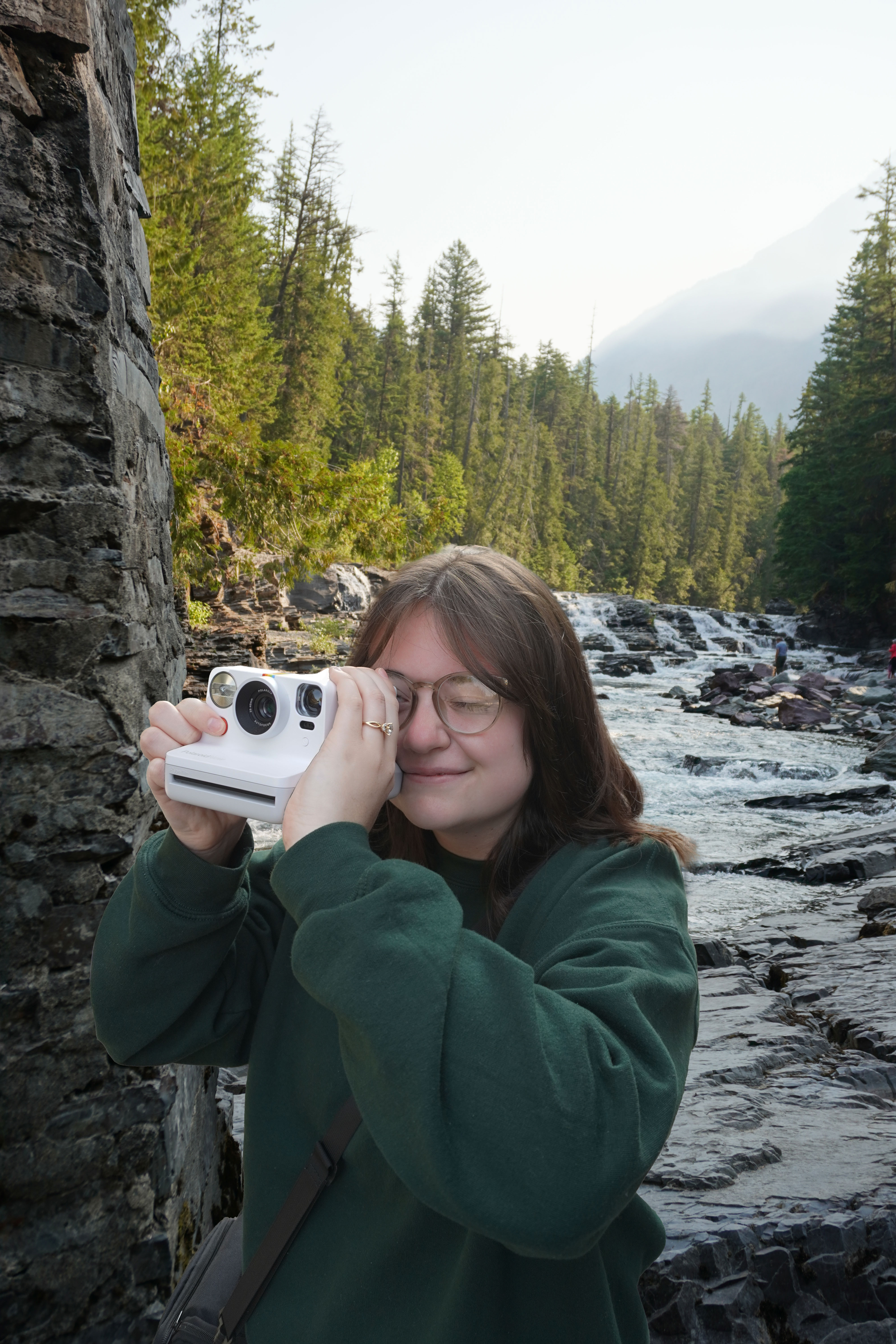 Photo of Kaylen taking a picture with a Polaroid camera in Glacier National Park